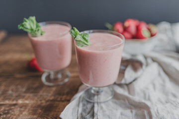 Fresh strawberry smoothie with mint on a linen rag on a wooden background.