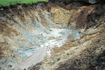 Dug hole in the ground is filled with water to the level. Swamp from the element that destroyed human activity. Stock abstract background