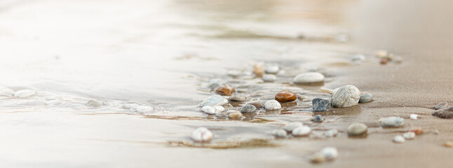 A close up view of smooth polished multicolored stones washed ashore on the beach. - obrazy, fototapety, plakaty