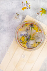 Fototapeta na wymiar Champagne cocktail with ice and flowers on a light gray background.