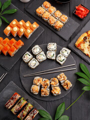 Sushi rolls on colored plates on a black background. A look from above.