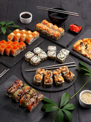 Sushi rolls on colored plates on a black background. A look from above.