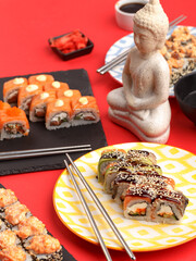 Sushi rolls on colored plates on a red background. A look from above.