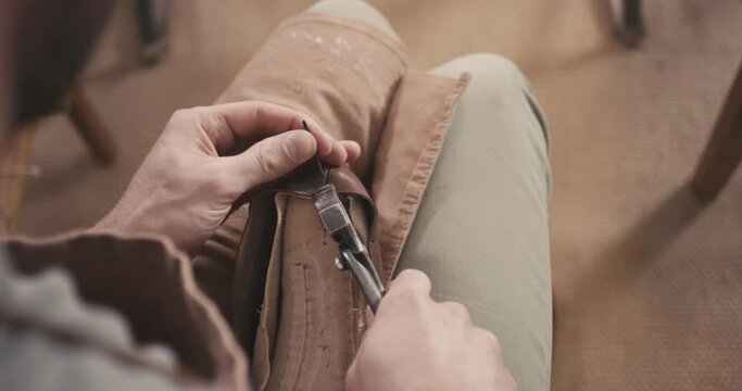 Traditional bespoke shoemaker nails leather upper on wooden shoe last with lasting pliers unrecognizable over shoulder