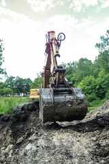 An excavator digs a large trench for building a house. A tractor digs a large lake that is already gaining water. Stock background for design