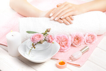Obraz na płótnie Canvas beautiful french manicure with roses, candle and towel on the white wooden table. spa