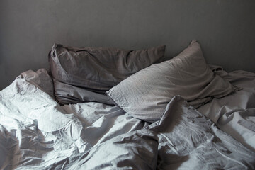 Gray bed linen. The weakening atmosphere, minimalism. Folds, drapes, natural cotton. Cozy bedroom.