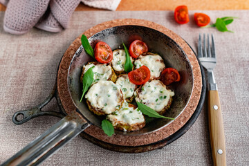 Pan-fried zucchini with garlic sauce and cherry tomatoes. Next to arugula, napkins, fork and mayonnaise. A colorful appetizer dish in a rustic setting