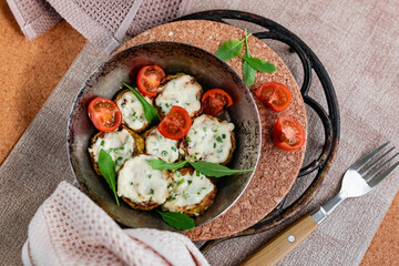 Pan-fried zucchini with garlic sauce and cherry tomatoes. Next to arugula, napkins, fork and mayonnaise. A colorful appetizer dish in a rustic setting