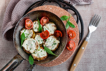 Pan-fried zucchini with garlic sauce and cherry tomatoes. Next to arugula, napkins, fork and mayonnaise. A colorful appetizer dish in a rustic setting