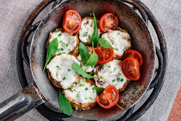 Pan-fried zucchini with garlic sauce and cherry tomatoes. Next to arugula, napkins, fork and mayonnaise. A colorful appetizer dish in a rustic setting