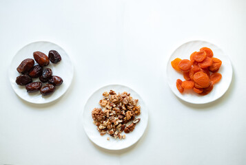 dates, dried apricots, walnuts on a white background. Useful candies without sugar. Ingredients for healthy sweets. Isolate with wholesome food.
