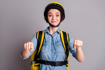 Portrait of positive courier girl biker drive imaginary scooter deliver cafeteria meal client customer corona virus home wear denim jeans shirt helmet isolated over gray color background