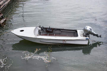a small motor boat is parked on the dock. The river is dirty, old Wharf