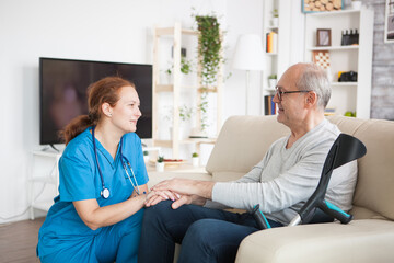 Obraz premium Female nurse smiling and talking with elderly age man in nursing home.