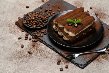 Classic tiramisu dessert on ceramic plate on concrete background