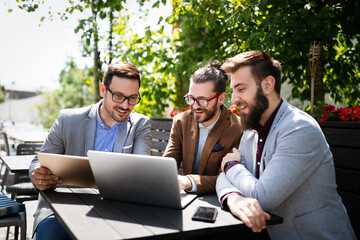 Cheerful happy businessmen using laptop at the meeting outdoor