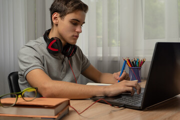 Handsome young man using laptop computer at home. Online shopping, home work, freelance, online learning, studying concept. Distance education