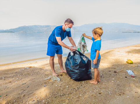 Young happy family activists collecting plastic waste on beach. Dad and son volunteers clean up garbage. Environmental pollution problems. Outdoor lifestyle recreation. Natural education of children