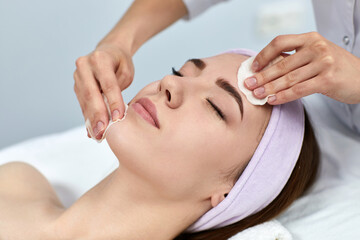 beautician cleanses female skin with a sponge. Perfect cleaning, woman is relaxing. spa treatment skincare face.