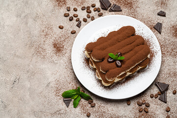 Classic tiramisu dessert on ceramic plate on concrete background