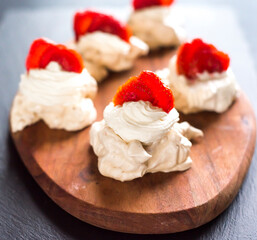 Pavlova dessert, the meringue with strawberries on black.