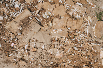 The texture of broken tiles, stones on the sandy brown ground. Top view of the devastation....