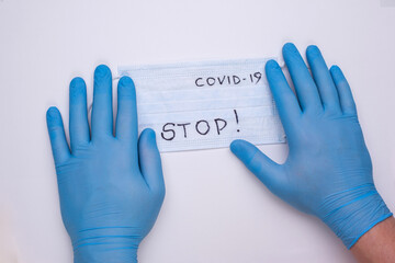 Hands in blue medical gloves lie on a medical mask. Inscription stop on a medical mask. Healthcare, medicine, doctor. Social distancing.