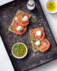 Mozzarella cheese, tomatoes and  pesto bruschetta on light marble background, top view. Pesto and sandwiches