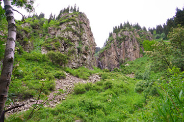 Beautiful waterfall in the mountains. Eco Tourism, eco travel. Mountain landscape, valley of mountains. Waterfall among stones and rocks.