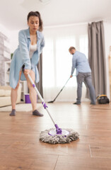 Fototapeta premium Cleaning apartment floor with mop by young wife.