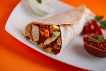 Grilled chicken in sandwich from fresh pita bread with onion and greens on  white plate