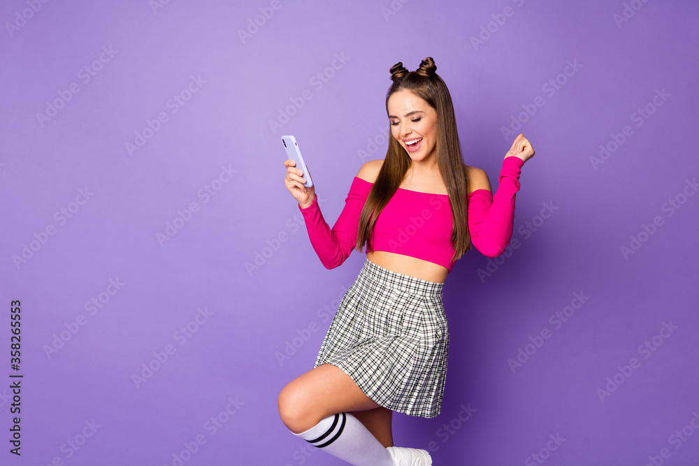 Poster Photo of pretty youngster crazy lady two funny buns hold telephone celebrate money income wear pink off-shoulders cropped top plaid short skirt isolated purple color background