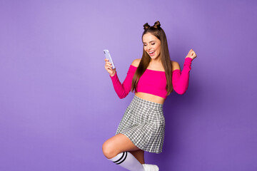 Naklejka premium Photo of pretty youngster crazy lady two funny buns hold telephone celebrate money income wear pink off-shoulders cropped top plaid short skirt isolated purple color background