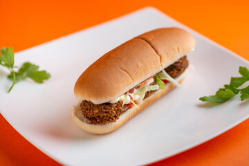 Turkish hot dog with falafel patties,thick layer of hummus, salad leaves,cucumbers,tomatoes and onions