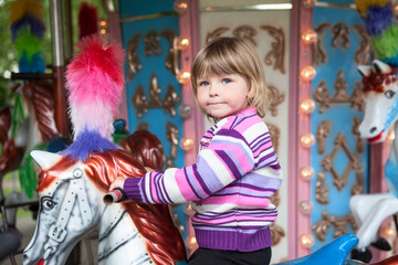 Obraz na płótnie Canvas Little girl riding a carousell horse, moving Merry-Go-Round