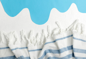 Top view of striped blanket and paper ocean as a symbol of vacation and beach, white surface