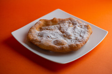 Traditional Transylvanian hungarian pastry, deep fried dough langos  with sugar close up on white plate