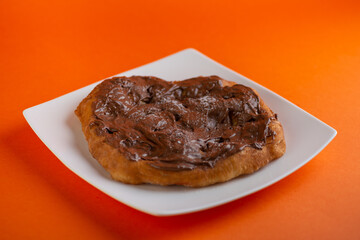 Traditional Transylvanian hungarian pastry, deep fried dough langos with cacao cream chocolate close up on white plate