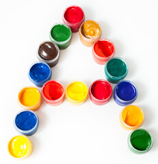 Colorful paints in plastic boxes in shape of A letter, white background