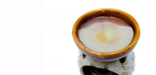 Aroma lamp on a white background. Lamp with aromatic oils on a white background. A man’s hand sets a candle in an aroma lamp