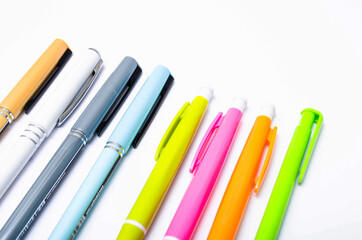 A large pile, the number of ballpoint pens of different colors on a white background. Pens for writing in close-up on a white background at an angle