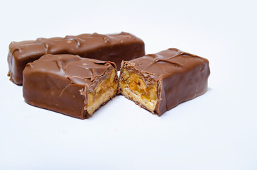 Two small snickers bars weighing 50 grams without packaging in macro are lying next to each other. Snickers one whole bar and another cut in half in macro. Chocolate cut in half close-up