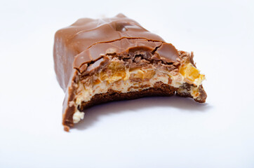 A piece of sneakerskie bitten on a white background teeth marks. One bar on a white background with bite marks. The malnourished snickers bar in macro