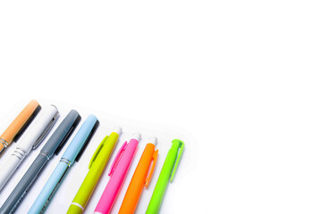 A large pile, the number of ballpoint pens of different colors on a white background. Pens for writing in close-up on a white background at an angle