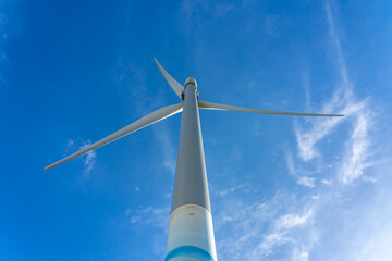 Close-up wind turbines or wind energy converter in sunny day with blue sky and white clouds