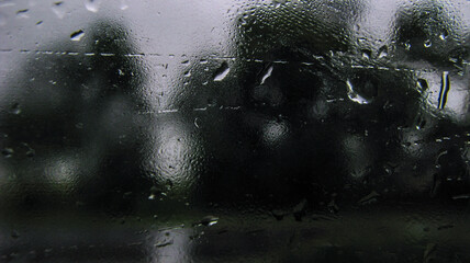 Drops on glass overlooking the street. Car window and the road behind it. Urban theme stock photo for design