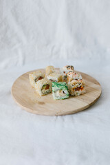 Sushi rolls on a wooden board with chopsticks on a white background. Stylish composition with sushi.