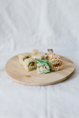 Sushi rolls on a wooden board with chopsticks on a white background. Stylish composition with sushi.