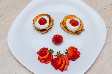 Delicious homemade pancakes with strawberries on plate on a light background